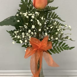 Orange rose arrangement with baby's breath in a glass vase and orange ribbon