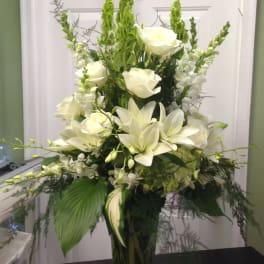 White lilies and roses in a tall glass vase