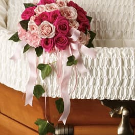 Pink and white rose bouquet with ribbon drapes on a casket