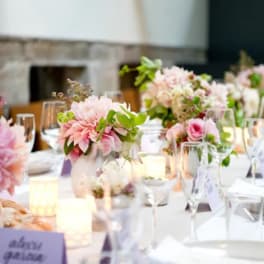 Pink floral centerpieces on a set dining table with candles and glassware