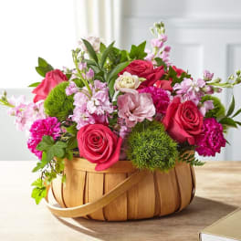 Basket arrangement of pink and red roses with carnations