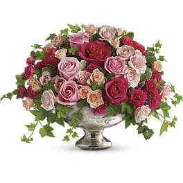 Pink and peach roses arranged in a silver pedestal vase