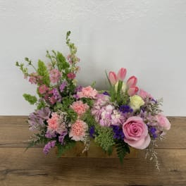 Pink and purple mixed flower arrangement in a rectangular wooden container