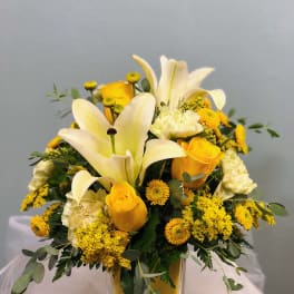 Yellow and white floral arrangement in a clear square vase