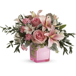 Pink roses and lilies arranged in a pink glass vase