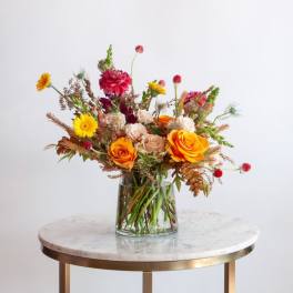 Mixed bouquet of roses and bright wildflowers in a glass vase