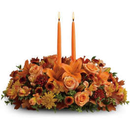 Orange floral centerpiece with two taper candles