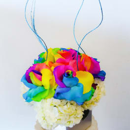 Rainbow rose bouquet with white flowers in a square vase