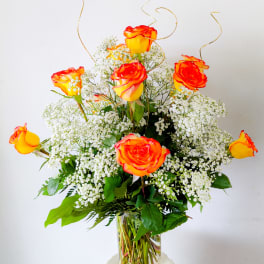 Orange-yellow roses in a clear glass vase with white baby's breath