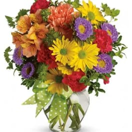 Colorful mixed bouquet in a clear glass vase with a green polka-dot ribbon
