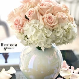 Blush pink roses and white hydrangeas in a round glass vase