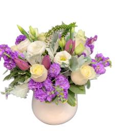 Purple and cream floral arrangement in a round vase