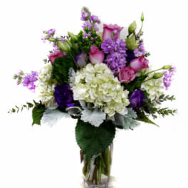 Purple and white floral arrangement in a clear glass vase