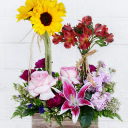 Mixed bouquet with sunflowers, roses, lilies, and red alstroemeria in a wooden box
