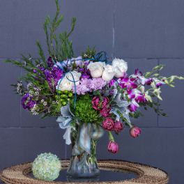 Mixed bouquet in a glass vase with white roses and purple orchids