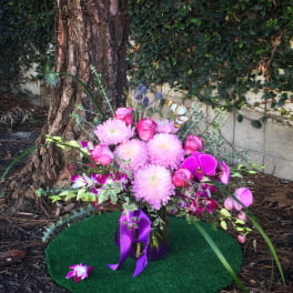 Pink floral arrangement with roses and orchids in a glass vase