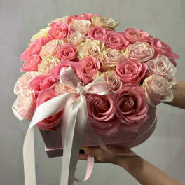 Round bouquet of pink and blush roses in a pink box with a white ribbon
