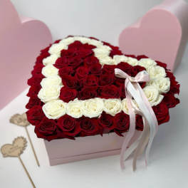 Heart-shaped box filled with red and white roses, tied with a pink ribbon