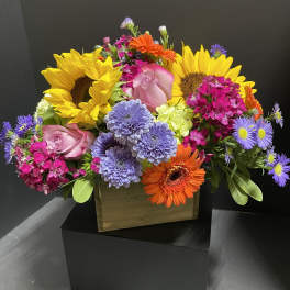 Colorful mixed bouquet with sunflowers, roses, and gerbera daisies in a box