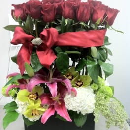 Red roses and pink lilies in a black box with a red ribbon