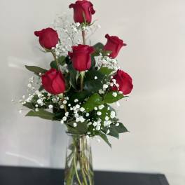 Red roses arranged in a clear glass vase with white baby's breath