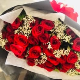 Bouquet of red roses with white filler flowers wrapped in paper
