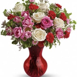 Bouquet of pink, white, and red roses in a red glass vase