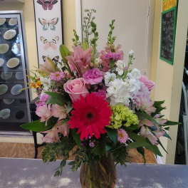 Mixed bouquet with pink lilies, roses, and a red gerbera daisy in a glass vase