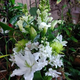 White lilies and snapdragons arranged in a glass vase