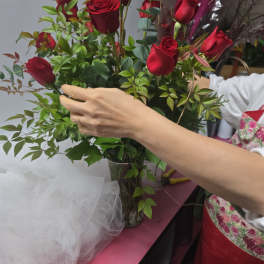 Red roses arranged in a clear glass vase with greenery