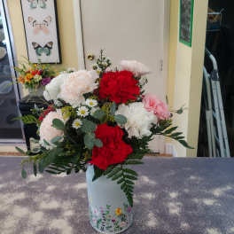 Mixed bouquet of carnations and daisies in a floral tin vase