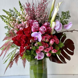 Mixed bouquet of red and pink roses with white calla lilies in a glass vase