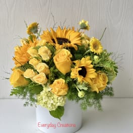 Yellow roses and sunflowers arranged in a white vase