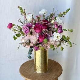 Pink and white floral arrangement in a gold vase