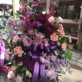 Large purple and pink floral arrangement with a satin ribbon