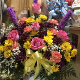 Pink roses and mixed daisies in a white vase with a yellow bow