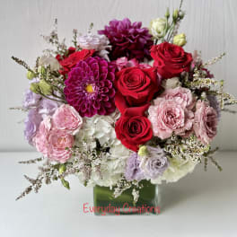 Mixed bouquet of red, pink, and white flowers in a glass vase