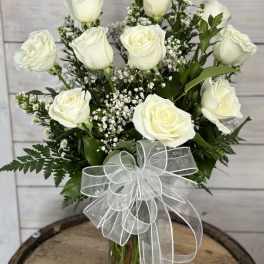 White roses in a clear glass vase with a sheer white bow