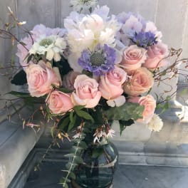 Pink roses and pastel blooms arranged in a glass vase