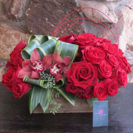 Red rose arrangement with pink orchids in a wooden box
