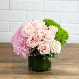 Pink and white flowers arranged in a green glass vase