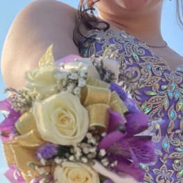 Girl wearing a purple dress holds a wrist corsage with cream roses and purple flowers