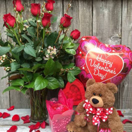 Red roses in a glass vase with a teddy bear and Valentine balloon