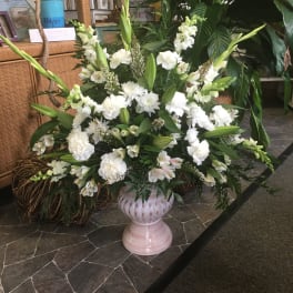 Large white floral arrangement in a pink pedestal vase