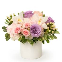 Pastel roses and white orchids arranged in a white vase