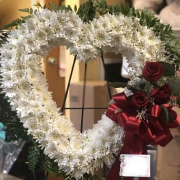Heart-shaped white chrysanthemum wreath with red roses and a red ribbon
