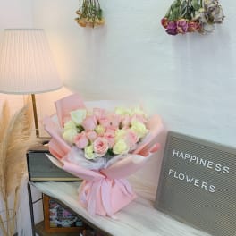Pink and white rose bouquet wrapped in pastel paper with a ribbon