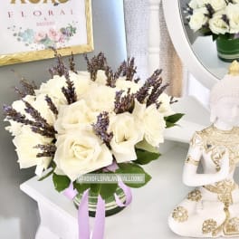 White rose bouquet in a striped vase with purple accents
