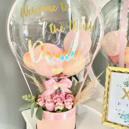 Pink roses in a round box with a clear balloon above