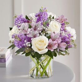 Bouquet of white roses, purple flowers, and pink alstroemeria in a glass vase